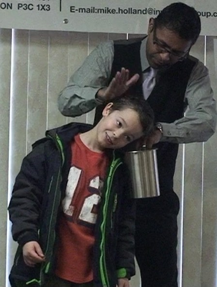 Wij doing a coin trick with a young guest